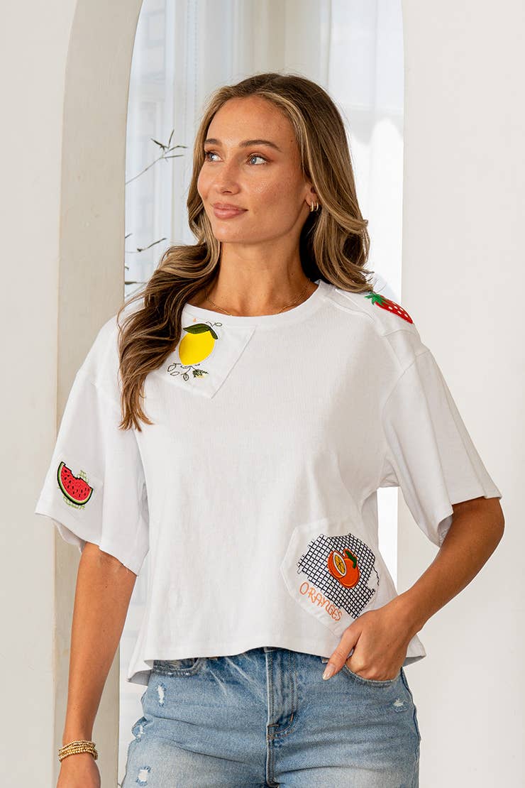 Woman wearing a white t-shirt with colorful designs, standing against a light background
