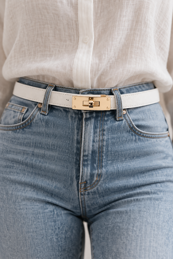 Close-up of blue jeans with a gold belt buckle and white shirt.