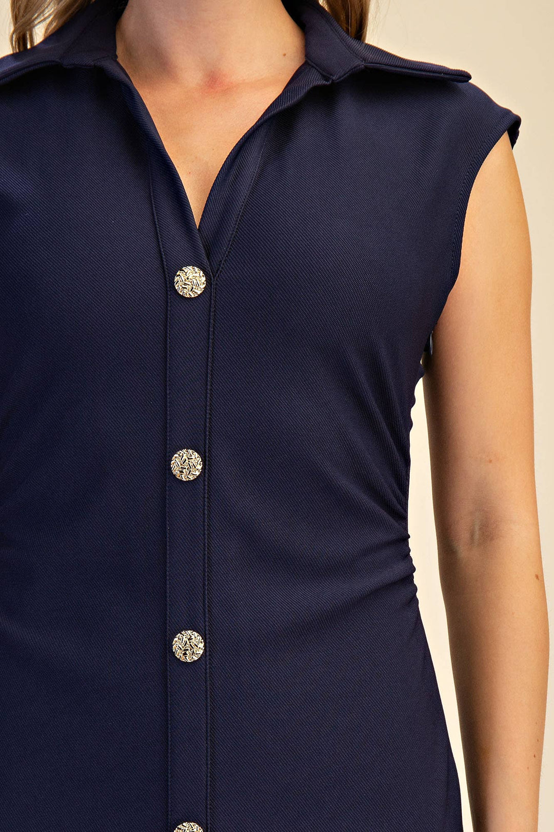 Navy blue cap sleeve dress with decorative buttons on a beige background