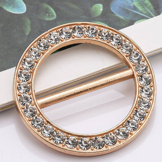 Gold circular brooch with crystal stones on a white surface