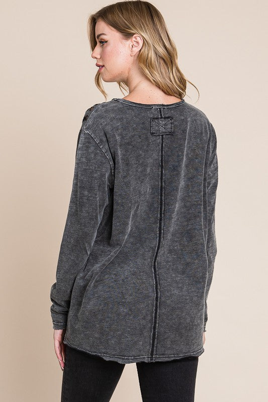 Woman wearing a gray distressed sweater on a beige background