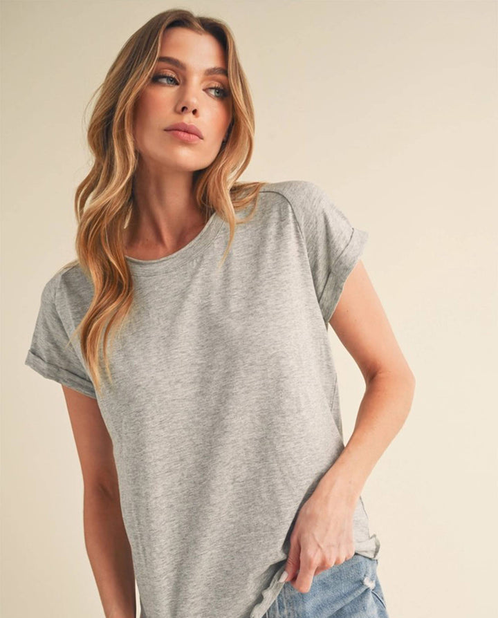 Woman wearing a gray t-shirt and denim shorts on a beige background