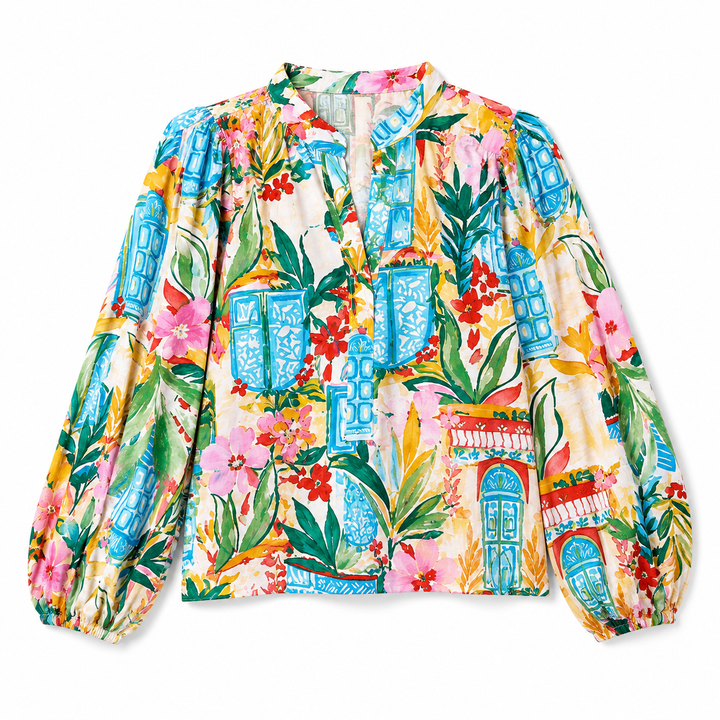 A long-sleeve blouse with a vibrant, multicolor tropical print featuring blue lanterns, pink flowers, green leaves, and red floral accents on a cream background.