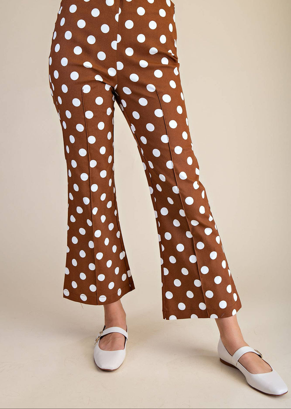 Brown pants with white polka dots worn by a person on a beige background