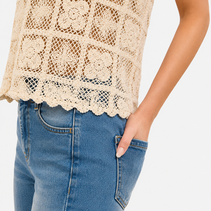 Beige lace top and blue jeans on a plain background