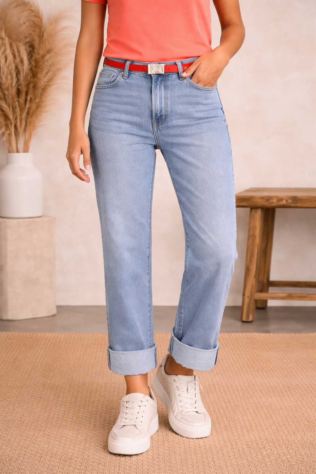 Person wearing light blue jeans and white sneakers in a casual setting.