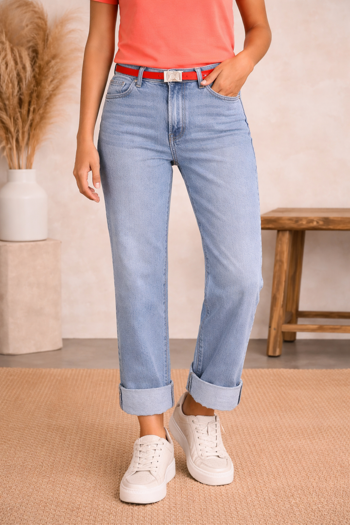 Person wearing light blue jeans and white sneakers in a casual setting.