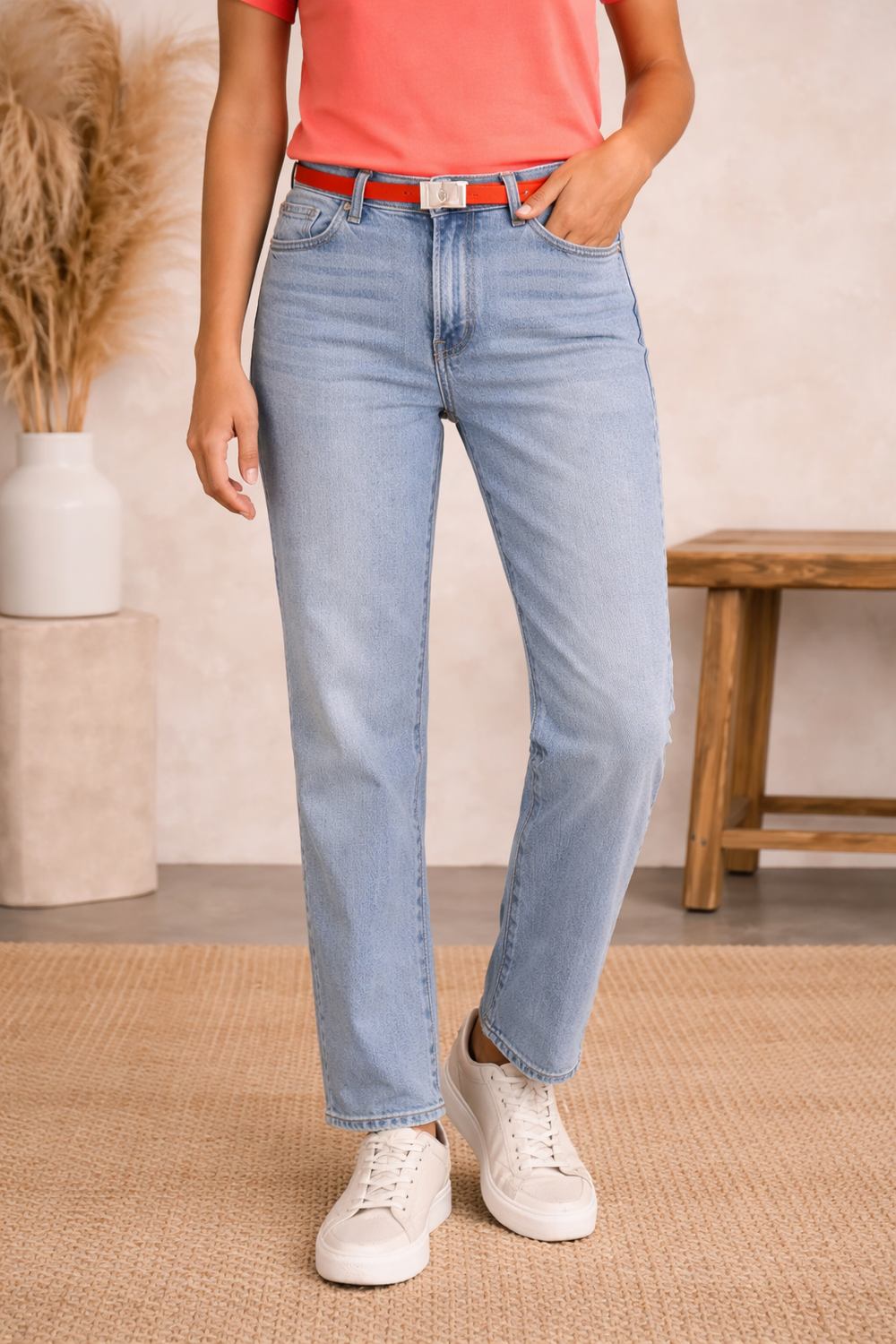 Person wearing light blue jeans and a red top in a casual setting.