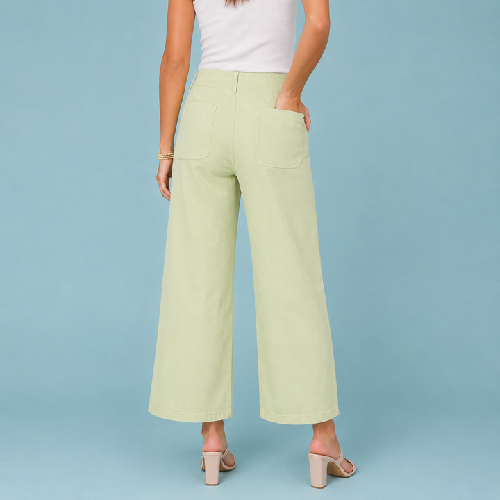 Person wearing light green wide-leg pants on a blue background
