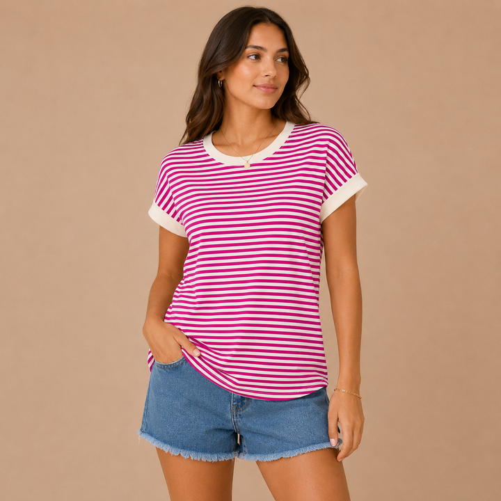 Woman wearing a magenta and white striped shirt with denim shorts on a beige background