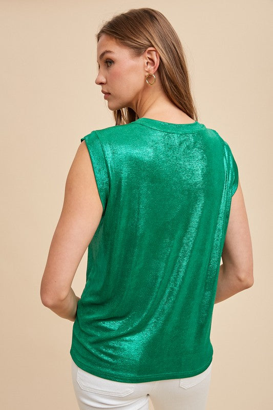 Woman wearing a green metallic sleeveless top against a beige background