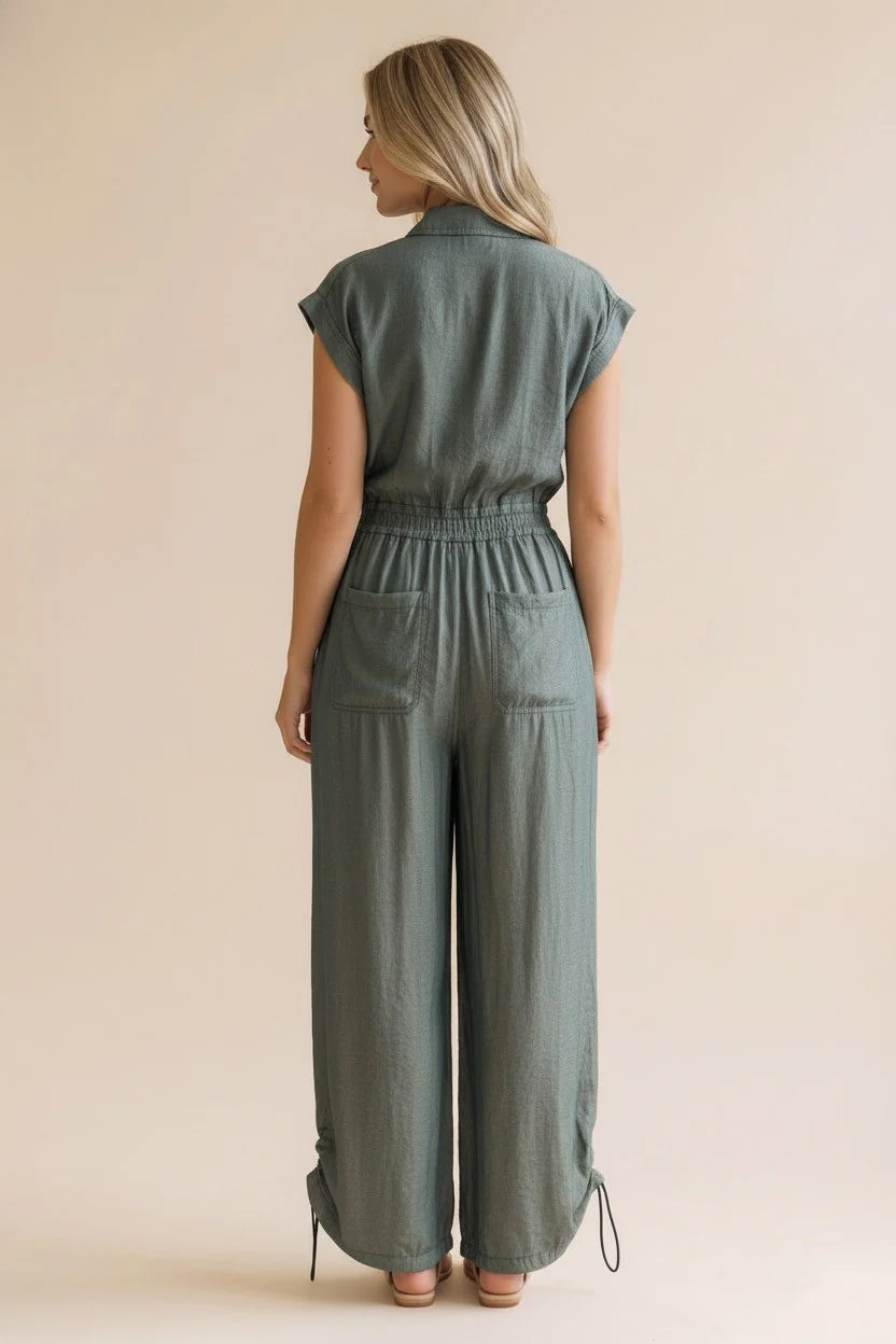 Woman wearing a green metallic shimmer jumpsuit against a beige background