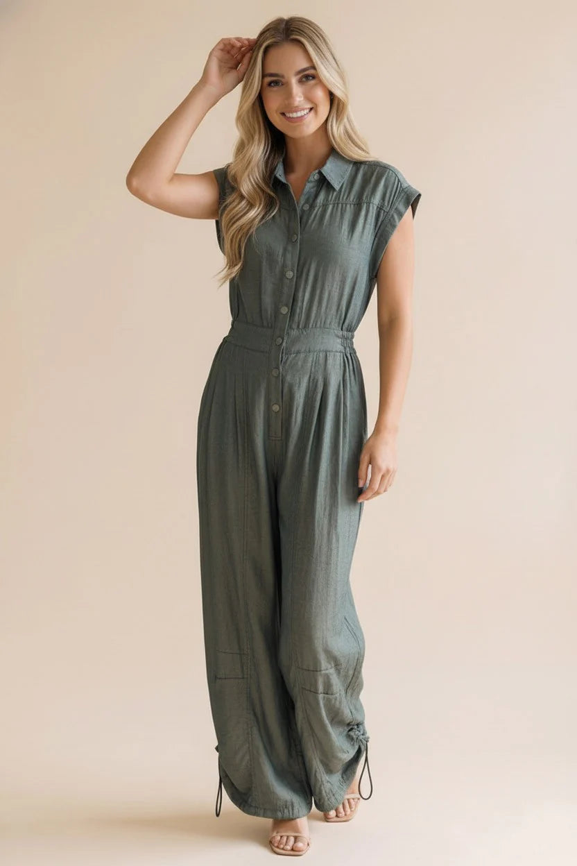Woman wearing an olive green metallic shimmer jumpsuit against a beige background