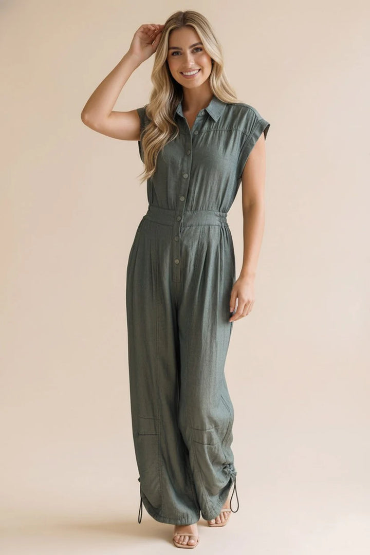 Woman wearing an olive green metallic shimmer jumpsuit against a beige background
