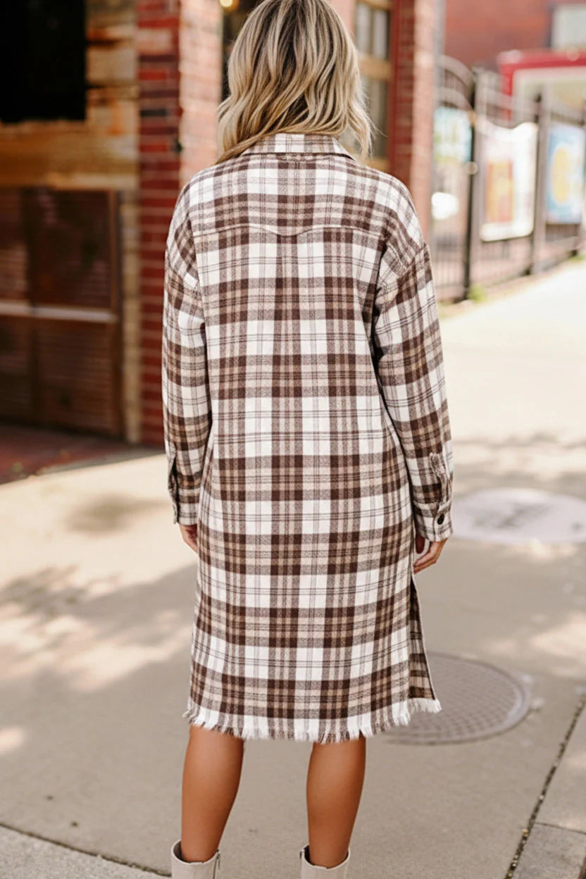 Person wearing a plaid dress on a sidewalk with a brick building in the background