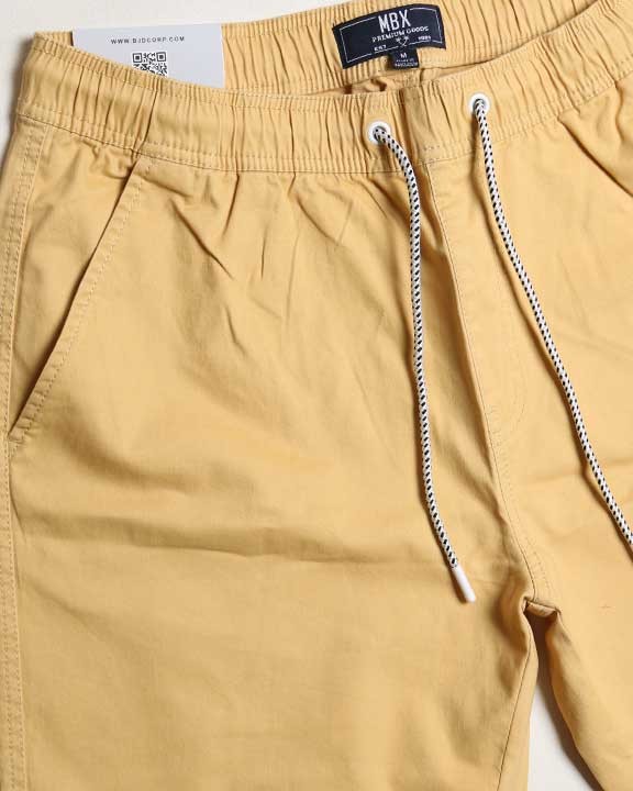 Close-up of mustard yellow pants with a brand label on a white background