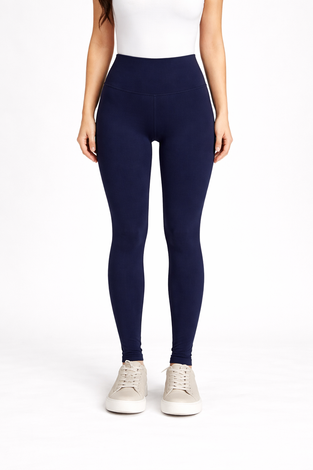 Person wearing navy leggings and white sneakers on a white background