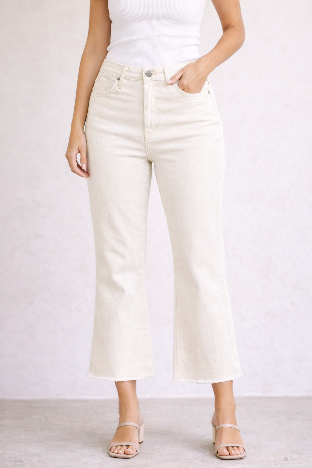 Person wearing white high-waisted jeans on a plain background