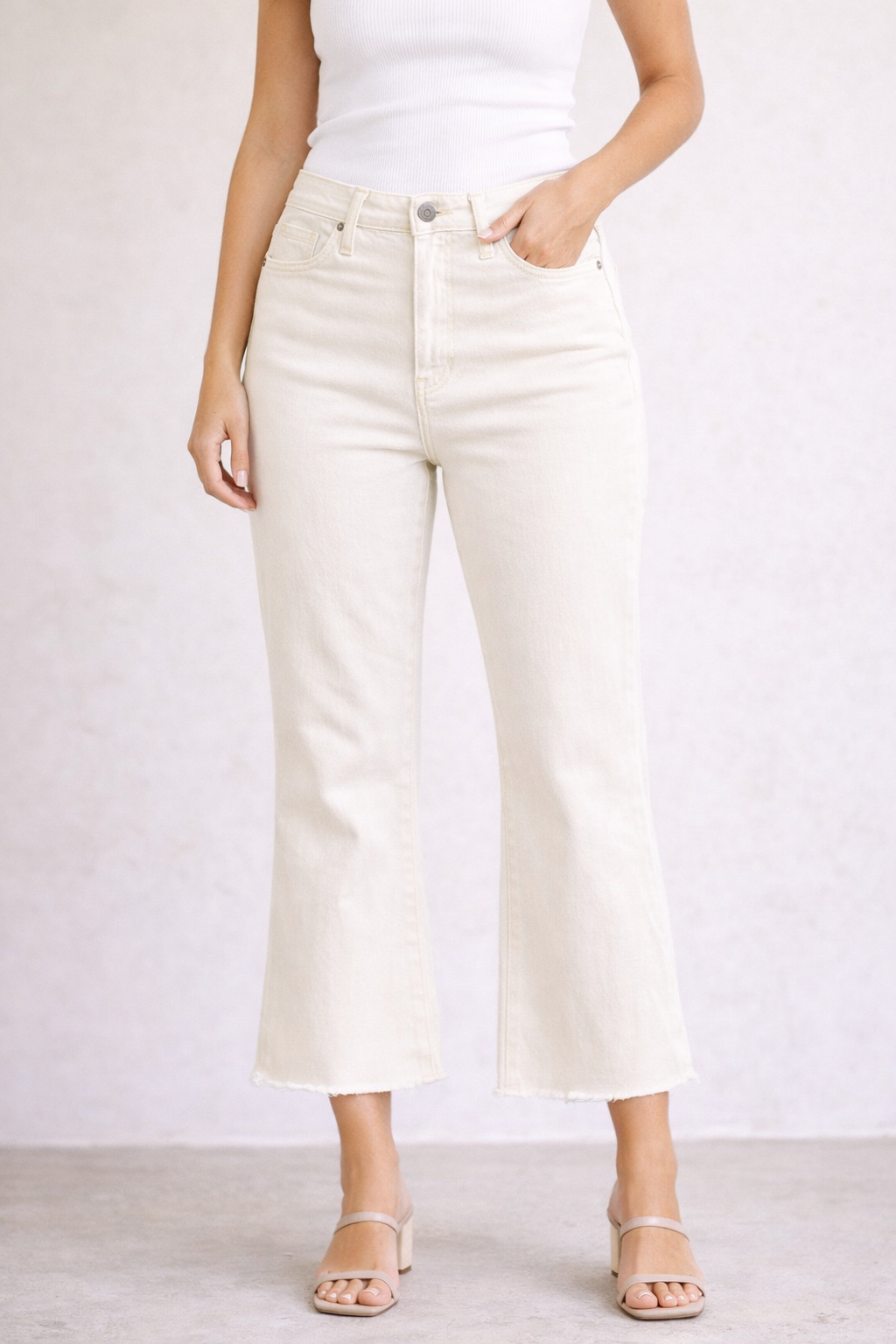 Person wearing white high-waisted jeans on a plain background