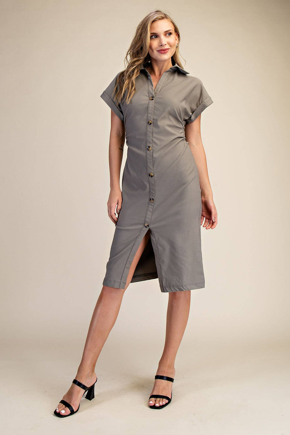 Woman wearing a olive dress with a plain background