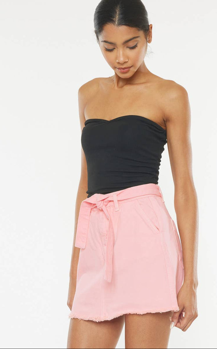 Woman wearing a black strapless top and pink skirt on a white background