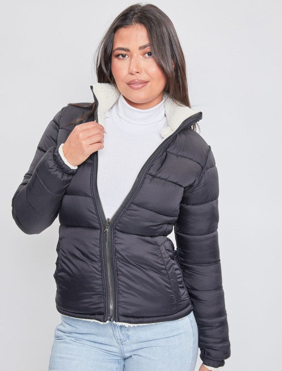 Woman wearing a black puffer jacket with a white interior on a plain background