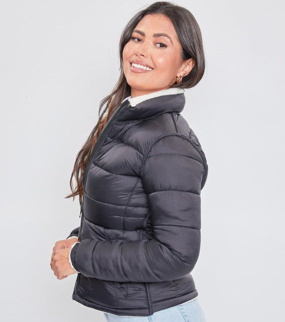 Woman wearing a black puffer jacket on a light gray background
