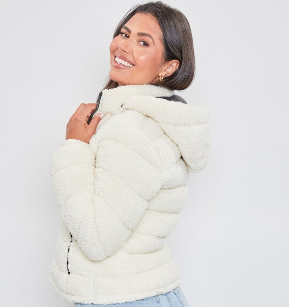 Woman wearing a cream puffer jacket against a white background