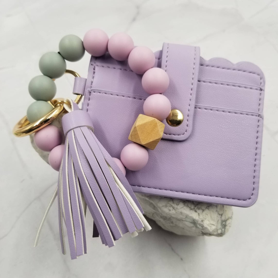 Purple wallet with a beaded keychain on a light gray background