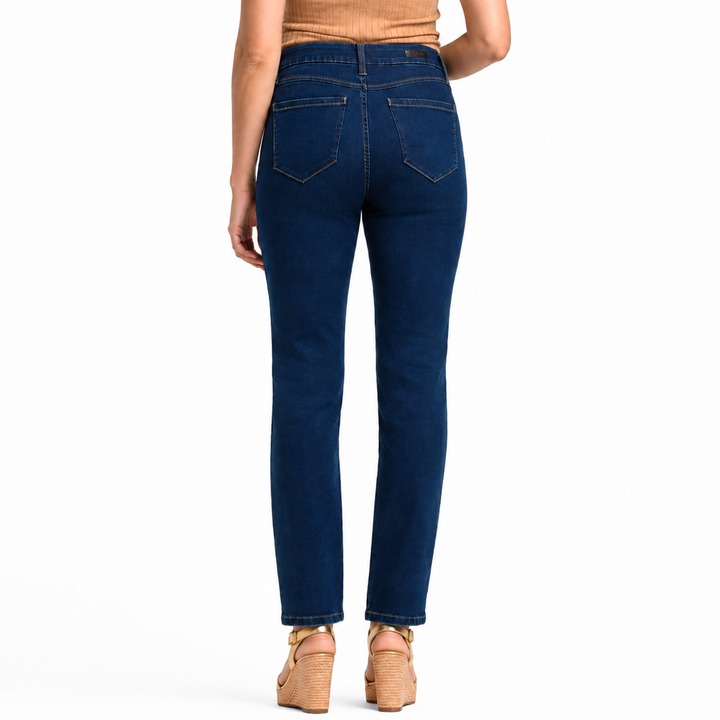 Rear view of a model wearing dark blue straight-leg jeans with a tan top and tan wedge sandals, shot against a solid white background.
