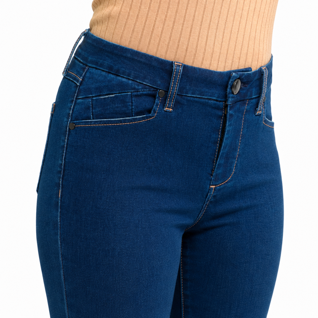 Close-up of a person wearing dark blue denim jeans with a beige ribbed top, showing the waistband, belt loops, button, and front pocket details against a plain white background.