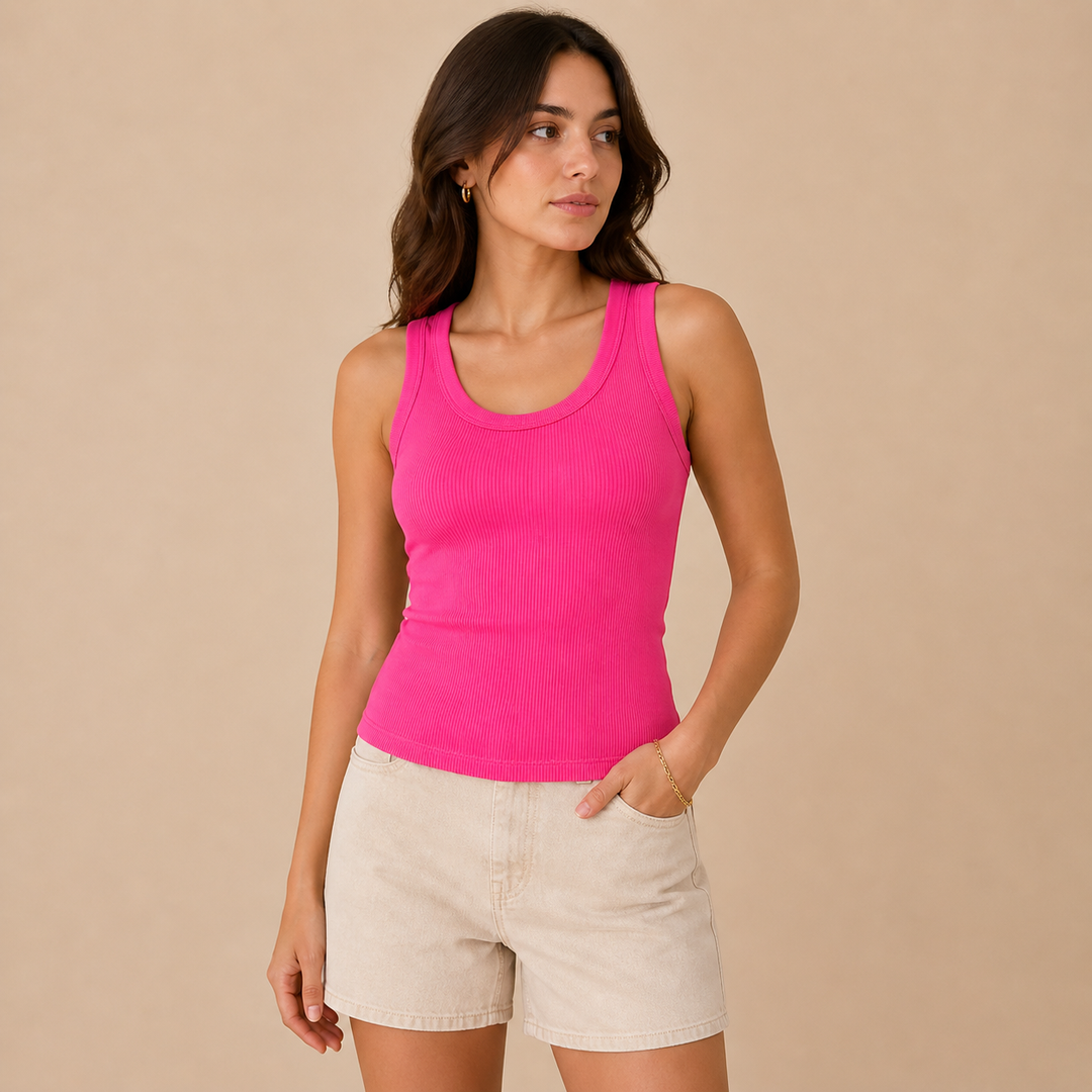Woman wearing a bright pink tank top and beige shorts against a beige background