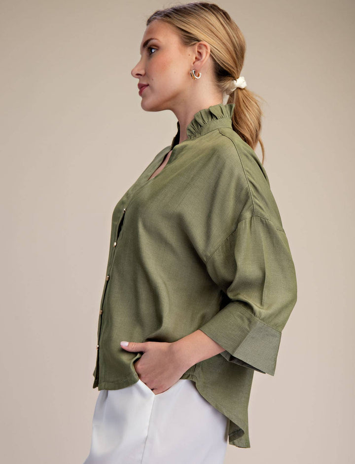 Woman wearing a green shirt and white shorts against a beige background