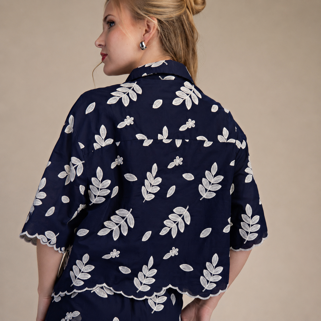 Woman wearing a navy blue shirt with white floral pattern on a beige background