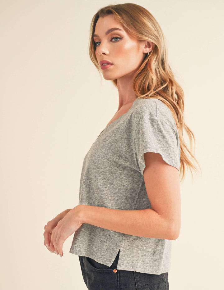 Woman wearing a gray short-sleeve top against a beige background
