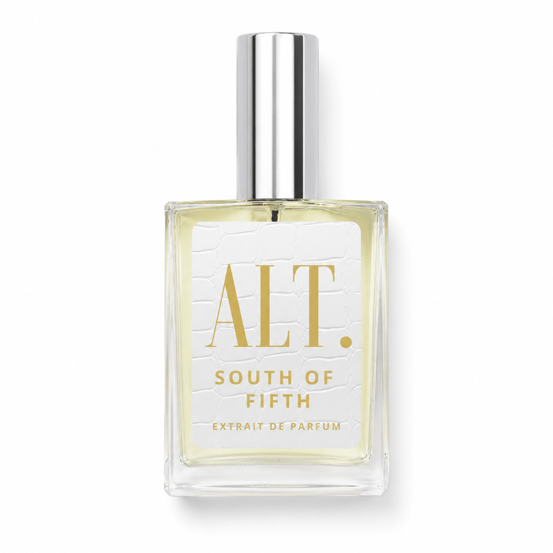 A clear glass bottle of ALT. South of Fifth Extrait de Parfum with pale yellow liquid, a white textured label with gold lettering, and a shiny silver cap, set against a plain white background.
