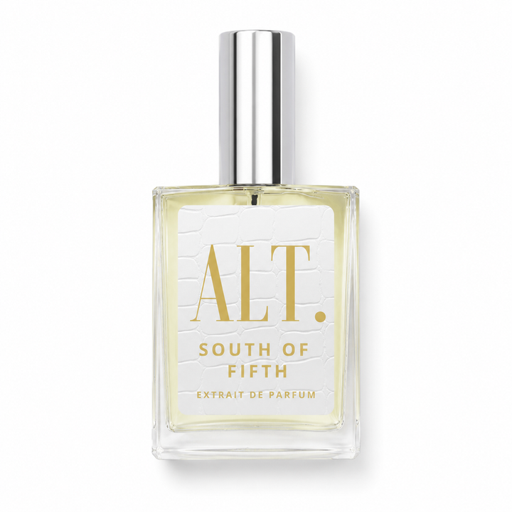 A clear glass bottle of ALT. South of Fifth Extrait de Parfum with pale yellow liquid, a white textured label with gold lettering, and a shiny silver cap, set against a plain white background.