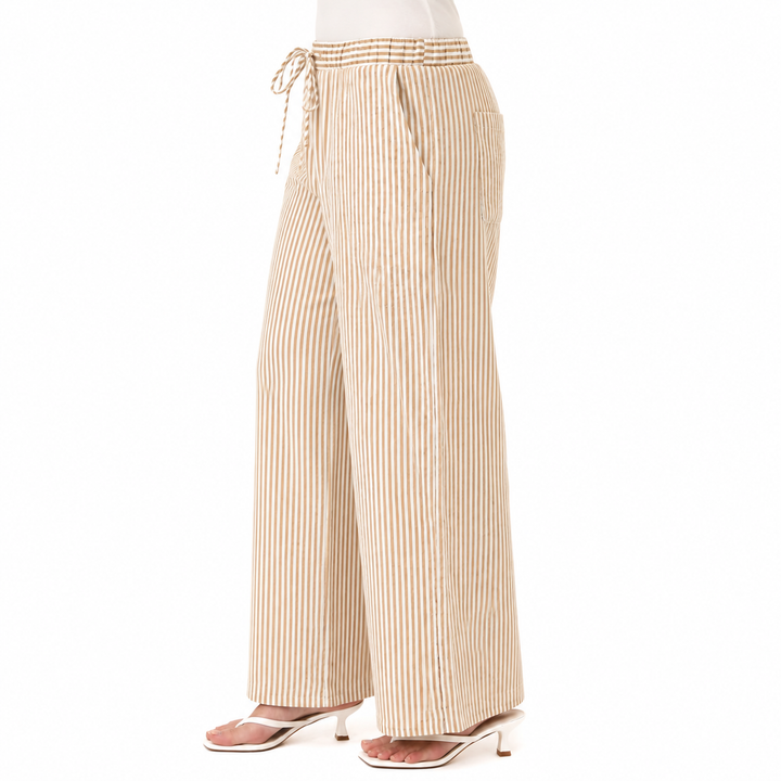 A person wearing beige wide-leg pants with thin brown vertical stripes, a matching striped drawstring waist, and clear high-heeled sandals, shown against a plain white studio background.