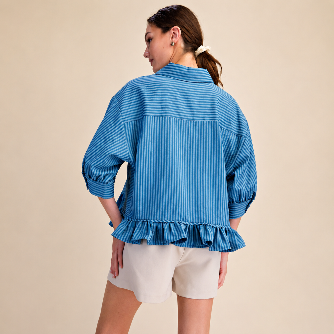 Woman wearing a blue striped blouse with ruffled details on a beige background