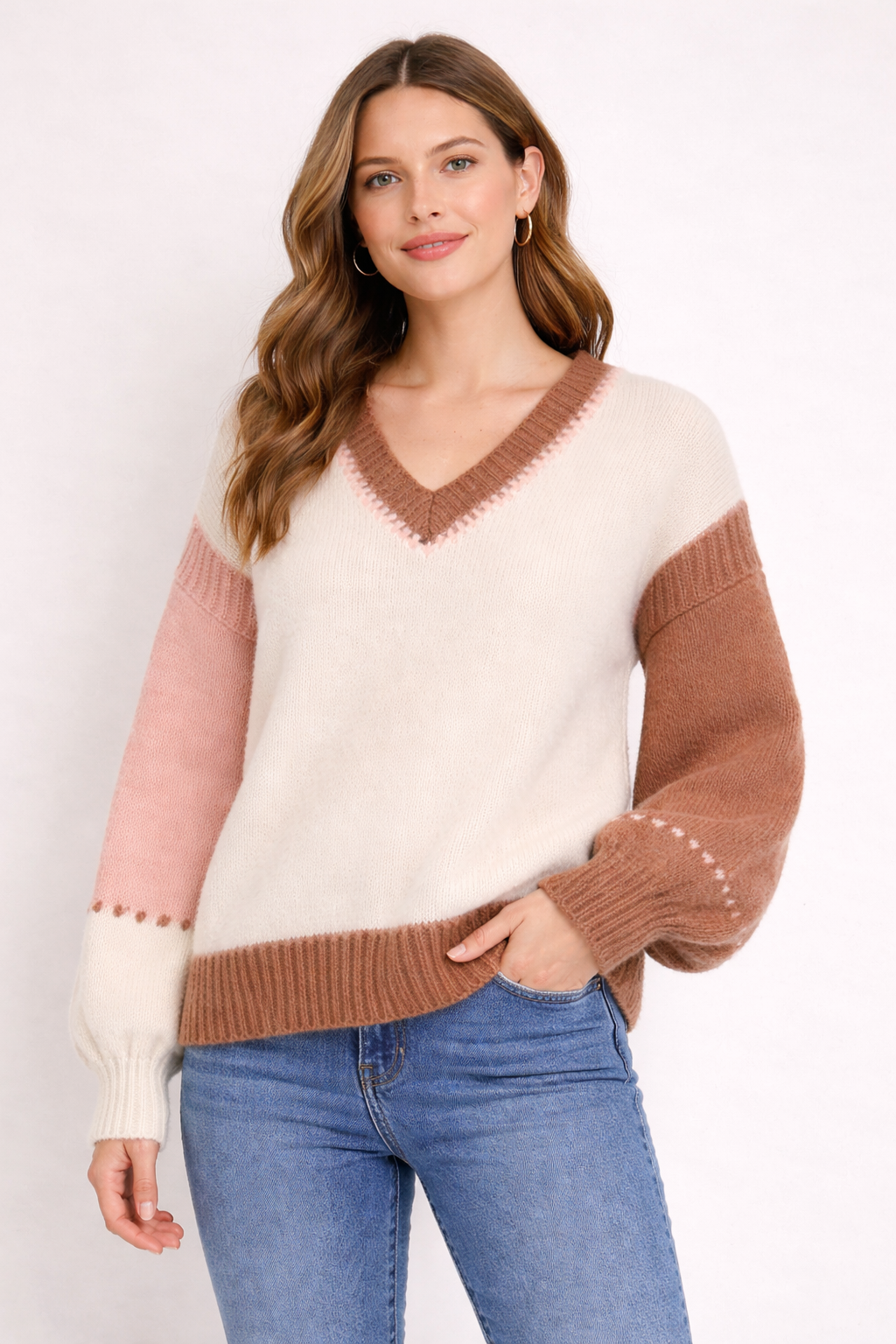 Woman wearing a color-blocked sweater with pink and brown sleeves against a white background