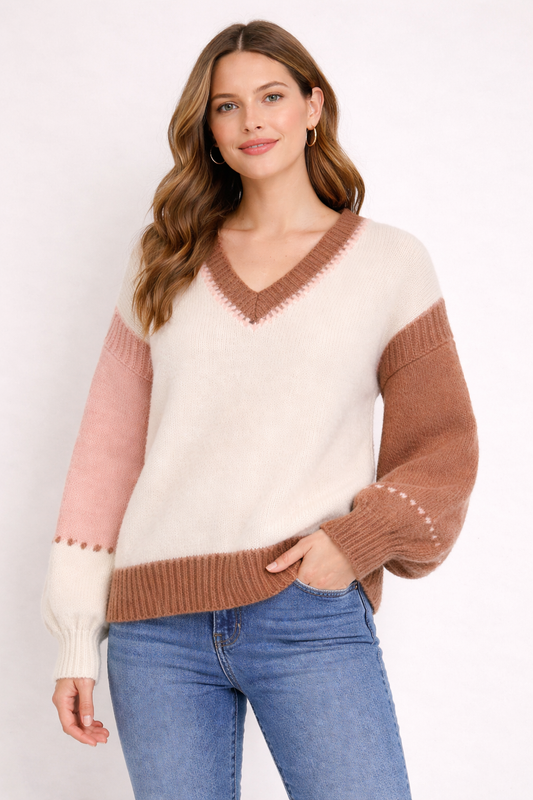 Woman wearing a color-blocked sweater with pink and brown sleeves against a white background