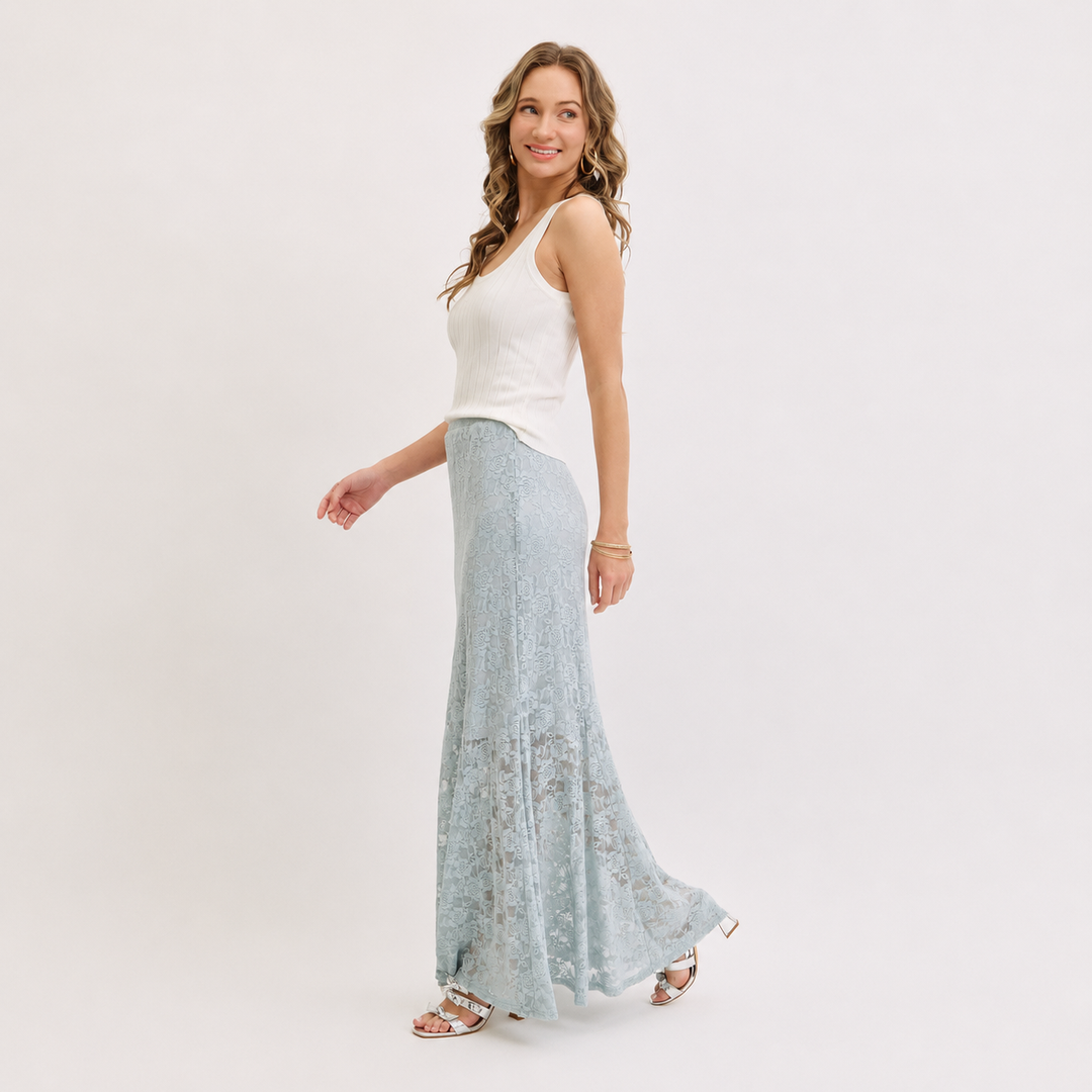 Woman wearing a white top and light blue lace skirt on a plain background