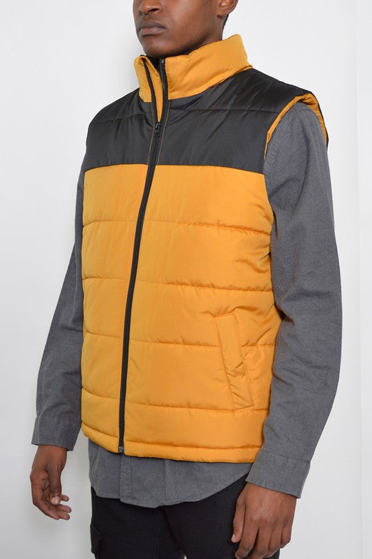 Person wearing a two-tone puffer vest with yellow and gray colors on a white background