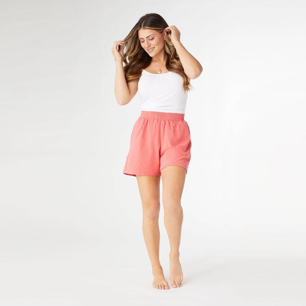 A female model wearing pink Weekend Brushed Pocket Shorts with a white tank top, standing against a white background.