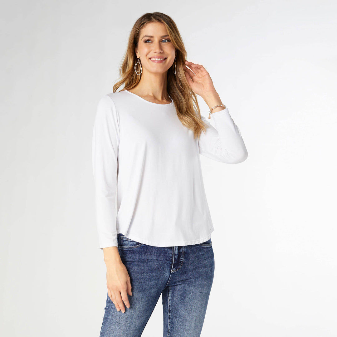 Woman wearing a white long-sleeve top and blue jeans on a white background