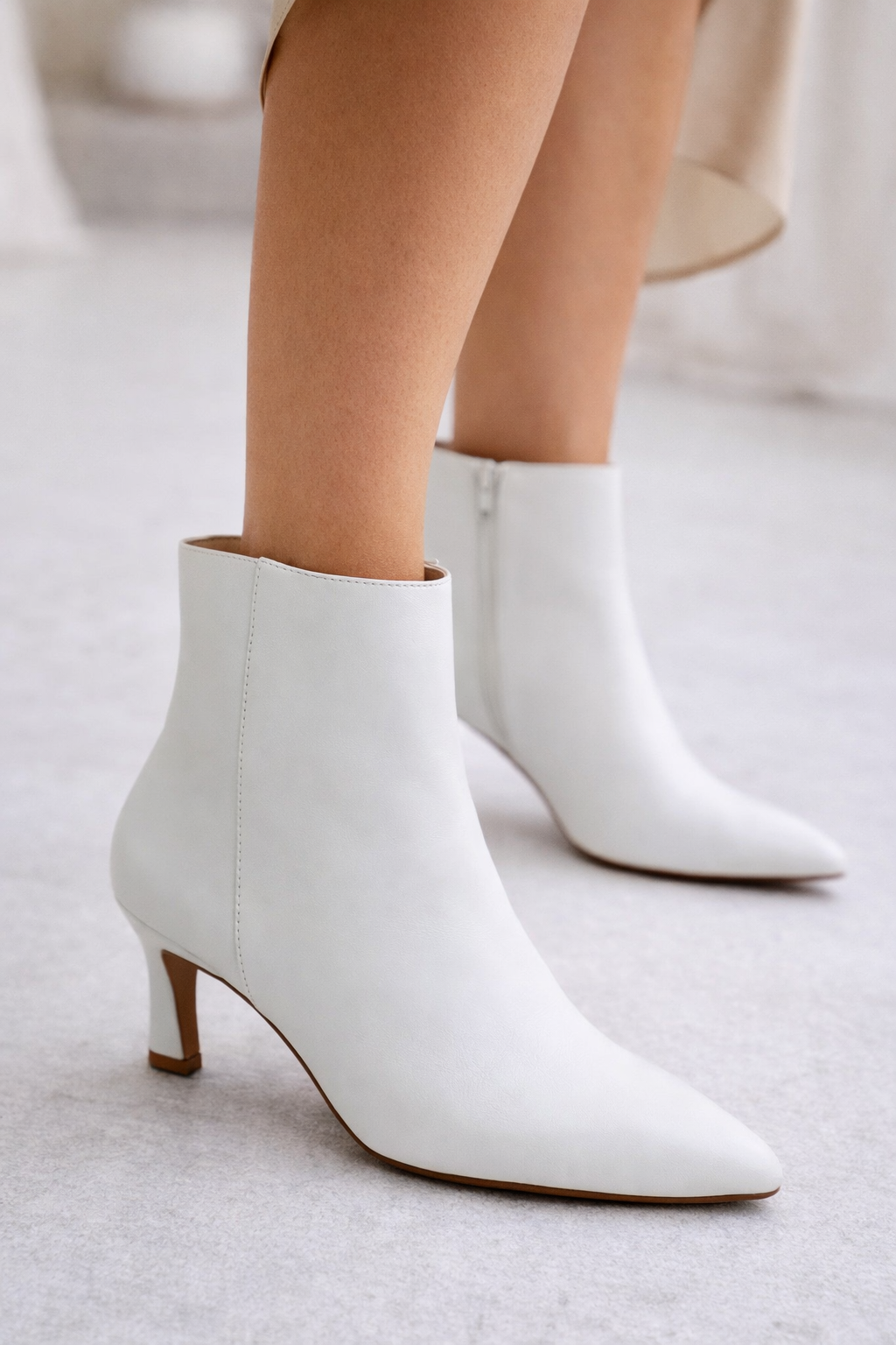 White ankle boots worn by a person on a light gray background