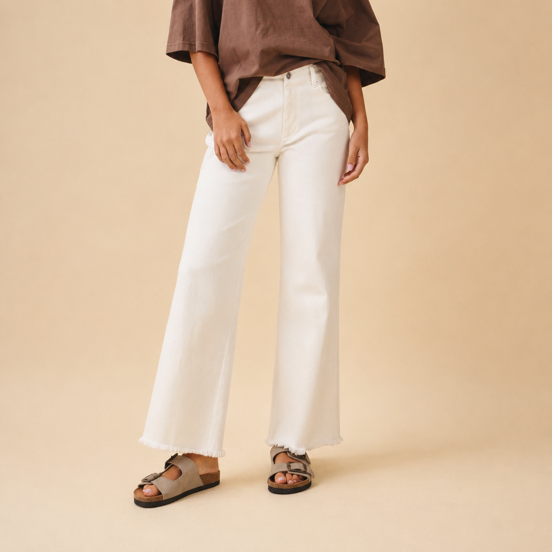 Person wearing white pants and a brown top on a beige background