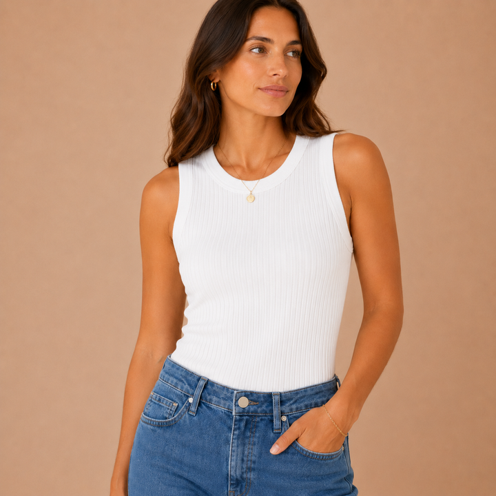 Woman wearing a white sleeveless top and blue jeans against a beige background