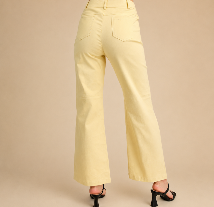 Light yellow pants worn by a person on a beige background